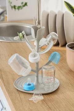 Baby bottle drying rack with pacifiers and clean bottles on kitchen counterto Stock Photos