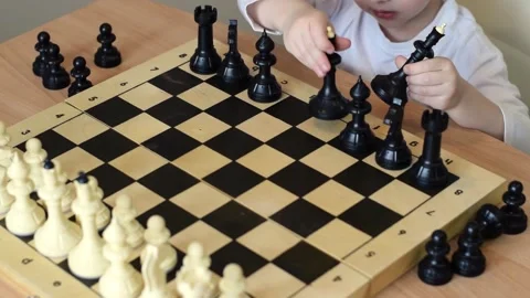 Baby boy arranges black chess pieces on the board at home. Joint family leisure. Stock Footage 150480861