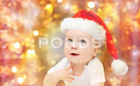 Baby boy in christmas santa hat over blue lights Stock Photos