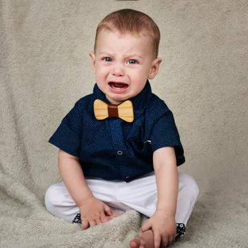Baby boy crying while looking at camera sitting on blanket Stock Photos