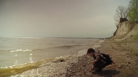 Baby boy having fun throwing stones into river. Boy throwing rocks into a river Stock Footage 274838620