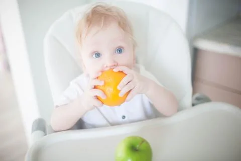 A baby boy in the kitchen eats fruit Foto stock