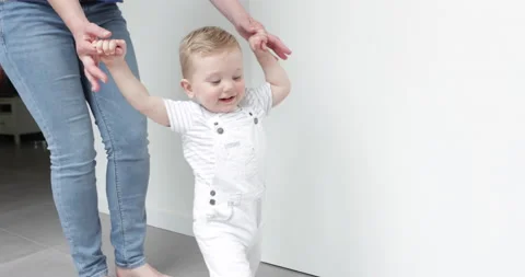Baby boy learning to walk by hand of his mother Video stock 154370826