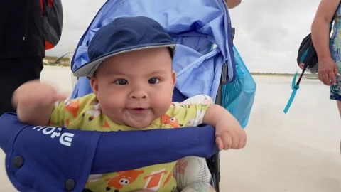 Baby boy making faces in stroller on beach in Ecuador 스톡 동영상 310008335