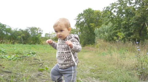 Baby boy is making his first steps in autumn  day in park outdoors. Stock Footage 68676451