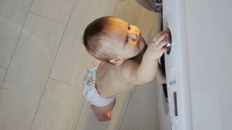 Baby boy next to washing machine Stock Footage 80216724