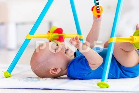 Baby boy on play mat. Child playing in gym. Stock Photos