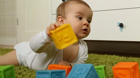 Baby boy playing with rubber bricks, crawling on green carpet Stock Footage 38141052