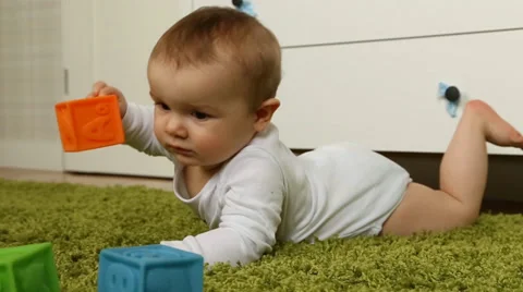 Baby boy playing with rubber bricks, crawling on green carpet Stock Footage 38142435