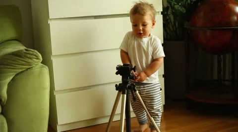 Baby boy is playing with tripod at the home Stock Footage