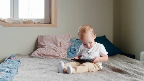 Baby Boy Sitting on Bed and Playing on Tablet 스톡 동영상 101040403