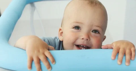 Baby boy smiling at camera while standing manege Video stock 77432684