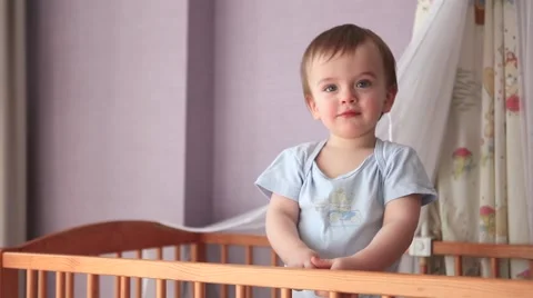 Baby Boy Standing in Cot and Showing Tongue Stock Footage 61878660