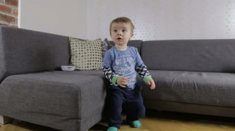 Baby boy stands in front of couch Stock Footage 44322477