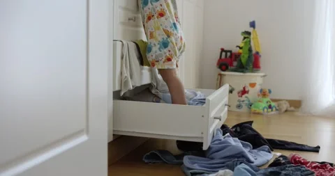 A baby boy throwing out clothes from closet Stock Footage 270538935