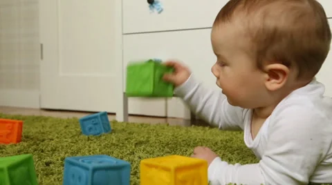Baby boy throwing rubber bricks, crawling on green carpet Stock Footage 38141133