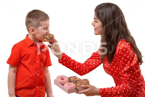 Baby boy toddler eat sweet donut. a woman is feeding a baby with a donut Stock Photos