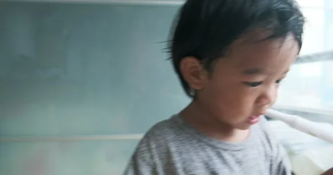 Baby boy use electronic toothbrush to Brush teeth byself in room kid Stock Footage 136448845