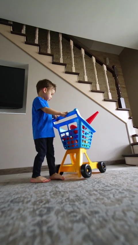 Baby boy walks backwards pulling a shopping cart. Stock Footage 290511676