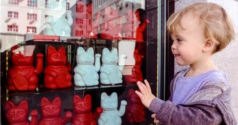 Baby boy waving hand while watching Maneki neko Stock Footage 93683446
