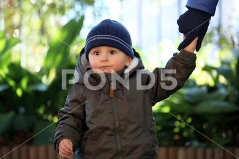 Baby Boy Wearing A Blue Knit Winter Hat And Green Winter Parka Stock Photos
