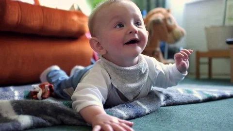 Baby boys lays on his belly and gets excited when mothe is about to pick him up. Stock Footage