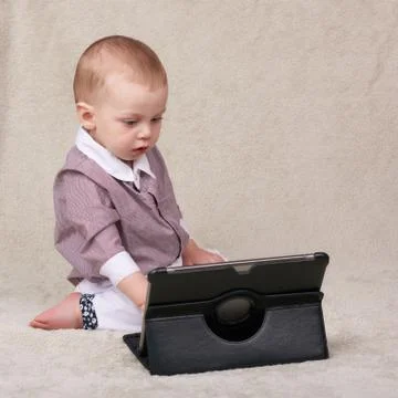 Baby busy using an electronic tablet while sitting on blanket Stock-Fotos
