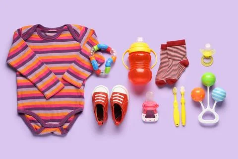 Baby care essentials flat lay with striped bodysuit, red shoes, sippy cup, pa Stock Photos