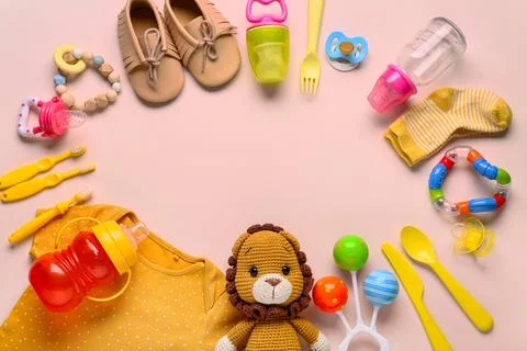 Baby care essentials flat lay with shoes, pacifier, bottle, and toys on pink  Stock Photos