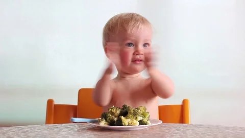 Baby clap hands, eats with pleasure steamed broccoli by fork and hand, happy kid Видео 88088423