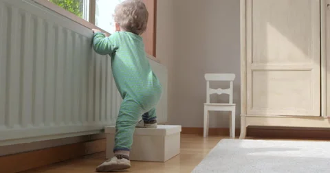 Baby climbs on box looking outside Video stock 50144544
