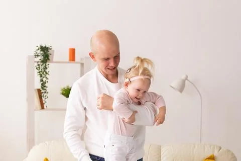 Baby with cochlear implants playing with her father at home. Deafness and Stock Photos