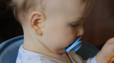 Baby considering plastic spoon Stock Footage 49602720