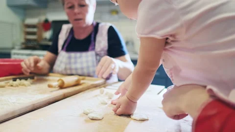 Baby cooking. Toddler girls learns pastry cooking on the kitchen with her family Stock Footage