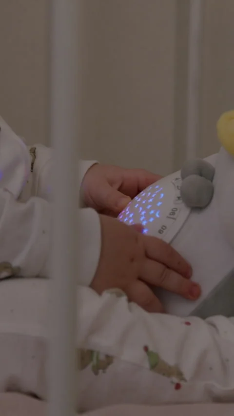 Baby in cozy crib interacts with plush penguin toy, showcasing playful Stock Footage 323497934