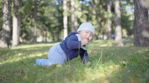 Baby crawls on the grass and eats leaves, smiling and playing Video stock 69023901