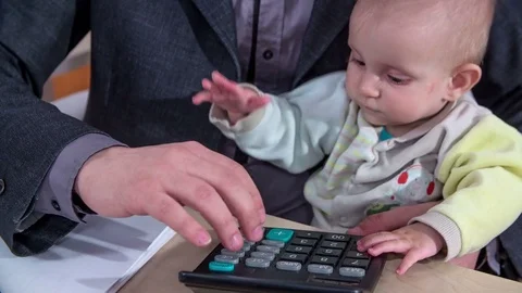 Baby daughter helps her daddy type on a calculator Stock Footage