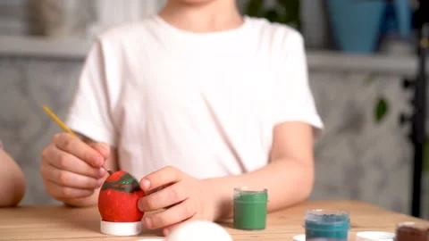 Baby decorates The Easter egg with paints and brush, sitting at the table, hands Stock Footage 151175474