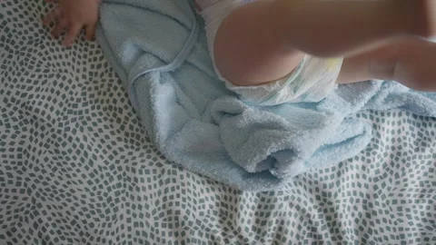 Baby in a diaper lying on a patterned blanket with a soft blue towel, Stock Footage 281310886