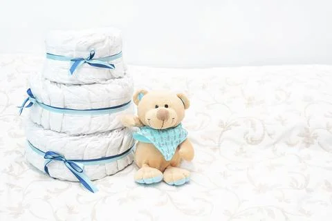 Baby diapers cake stack present with toy teddy bear on bed for the expectan.. Stock Photos
