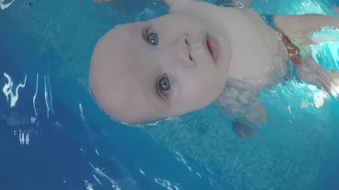 Baby doing the backstroke in the pool with the coach. Stock Footage 82558349