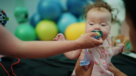 Baby with down syndrome getting physical therapy, a helping hand supporting the Stock Footage 339789225