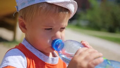 Baby drinks water from bottle outdoors Vídeo Stock 77102453