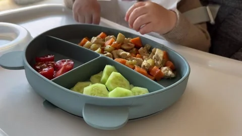 Baby eating first solid food, healthy baby meal on the table of high chair Stock Footage 304735735