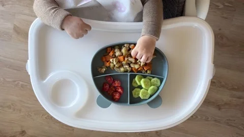 Baby eating first solid food, video of toddler self-feeding from above Stock Footage 304735740