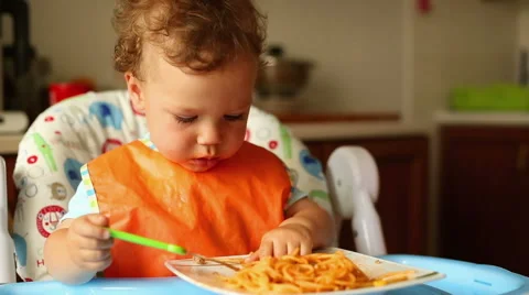 Baby is eating spaghetti in the kitchen Stock Footage 65433698
