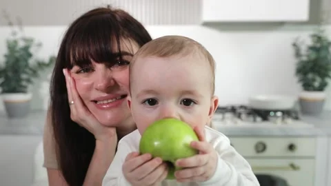 Baby eats apple with mom in kitchen Stock Footage 236087397