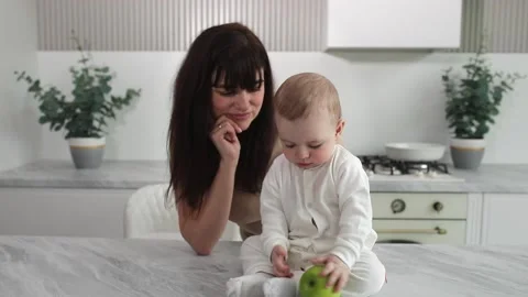 Baby eats apple with mom in kitchen Stock Footage 237916838