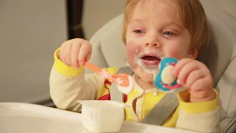 Baby eats cottage cheese with a spoon Stock Footage 147169266