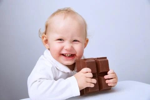Baby eats a large bar of chocolate Stock Photos